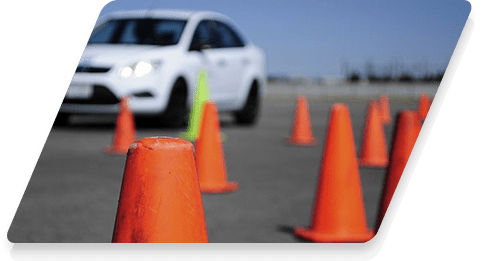 Voiture blanche entourée de cônes de signalisation.